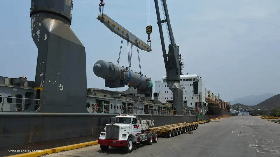 Heavy industrial component being lifted above a transport trailer