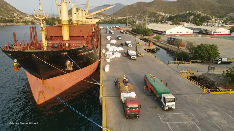 General cargo vessel beside trucks and quayside cargo